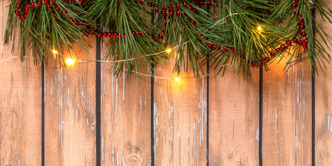 Christmas composition with pine branches, red beads, with lights, beautiful red Christmas balls at the top on a wooden background. Christmas concept. Selective focus. Top view. Banner.