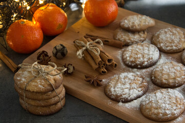 Christmas biscuits with festive decoration. Top view photo of homemade cookies, Christmas lights, tangerines, star anise and cinnamon sticks. 
