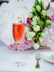 flowers and glass of rose sparkling outdoor, plate, fork, knife on the table. Cutlery, food, lunch, party concept