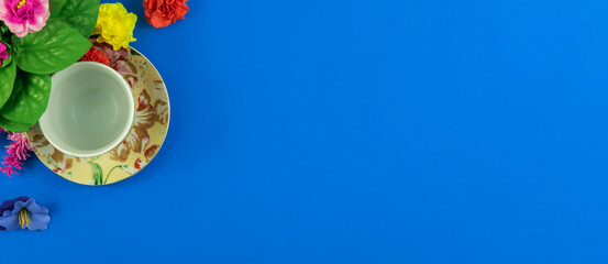 Flat design, blue background and empty tea service set, place for text, decorative flowers at border, top view banner