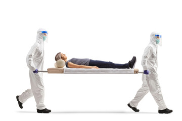 Health workers in hazmat suits carrying female patient on a stretcher