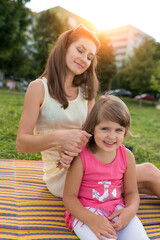 happy family, woman mother with daughter, girl of 5-6 years old, cheerful joyful picnic nature, parenting, emotions of happiness, delight, fun and joy. Summer in park sitting blanket stylish clothes.