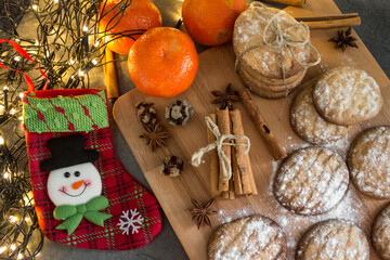 Christmas stocking, cinnamon sticks, tangerines and cookies on dark gray background with copy space. Festive decorations top view photo. 
