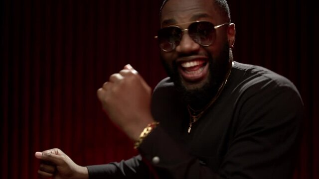 Close-up of an African American man dancing in the studio in a bright image. Portrait of a handsome guy dancing on a red background in a good mood. The expressive dancer moves effectively on the studi