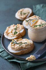 Sandwiches with smoked salmon and soft cream cheese pate or mousse with thyme and rosemary on a ceramic plate, green concrete background.