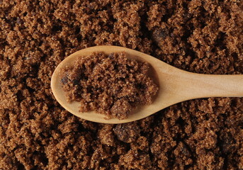 Dark sugar muscovado in wooden spoon background and texture