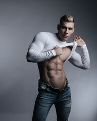 Studio portrait of sexy fitness guy in white shirt and blue jeans