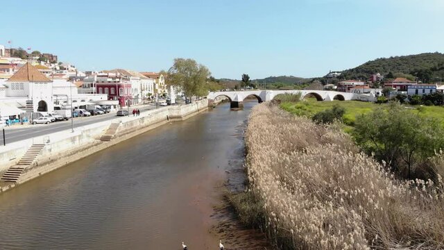 Fly over river on quiet sunny day. Quaint view of Silves, Algarve, Portugal