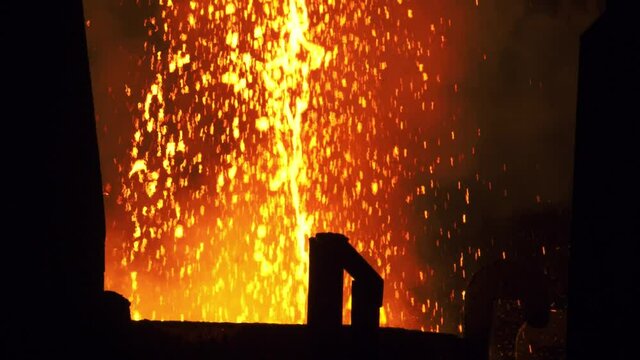 Liquid metal from blast furnace. metal casting process with high temperature fire in metal part factory. Foundry - molten metal poured from ladle into mold - emptying leftover.