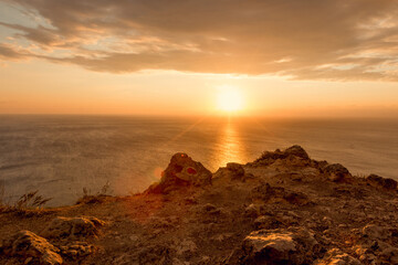 Seascape at red sunset. On the edge of a cliff. Summer-autumn. Horizontal photo. A soft picture. The view from the top