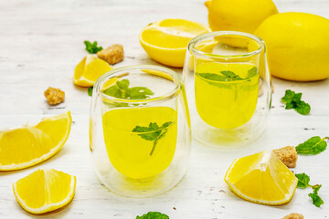 Fototapeta na wymiar Traditional Italian digestif: liqueur Limoncello with lemons and fragrant mint leaves