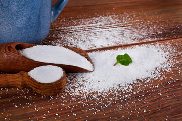 Blue ceramic cup, wooden scoops of sorbitol and fructose on a wooden background. Different...