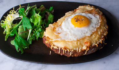 Croque madame or monsieur. Breakfast or brunch favorite: toast, with fried eggs, ham, cheese and hollandaise sauce. Served with potato hash. Classic French bistro or American restaurant entree.