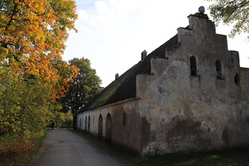 Old antique stone barn in the Latvian village of Auce among autumn trees on October 13, 2020