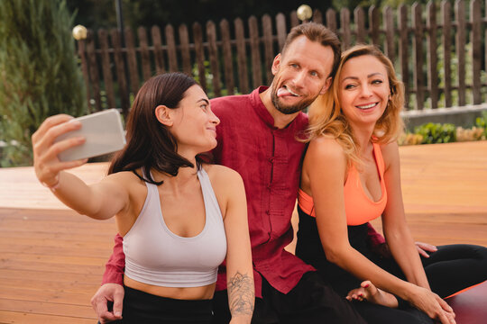 Happy fit friends taking selfie during workout outdoors in sporty outfit