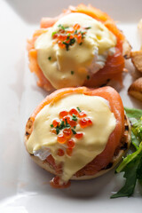 Eggs Benedict is Breakfast or brunch favorite: English muffin with poached eggs, ham, lox, spinach, cheese and Hollandaise sauce. Served with potato hash. Classic French bistro entree.