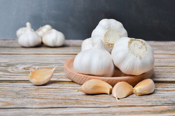 Fresh garlic on wooden plate isolated on black background. Selective focus.