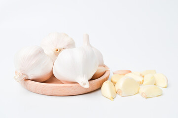 Fresh garlic on wooden plate isolated on white background. Selective focus.