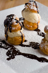 Profiteroles. Classic Italian dessert. Puff pastry filled with chocolate, vanilla and Carmel ice cream and topped with melted chocolate sauce and powdered sugar.