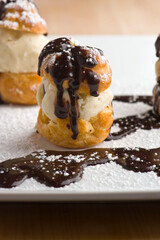 Profiteroles. Classic Italian dessert. Puff pastry filled with chocolate, vanilla and Carmel ice cream and topped with melted chocolate sauce and powdered sugar.