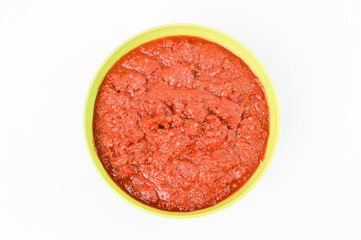 Top view of grinded chili pepper in a green bowl isolated on a white background.