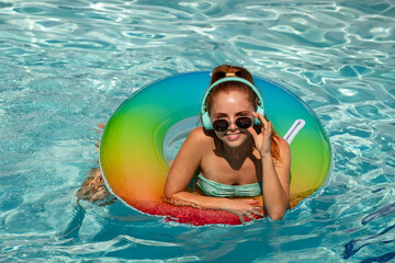 Summer girl in swimming pool. Cute funny teen relaxing with toy ring floating in a swimming pool having fun during summer vacation in a tropical resort.