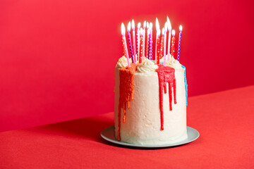 Birthday cake with candles on a red background. Festive buttercream cake
