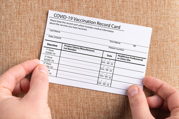 The coronavirus vaccination card is held in the hands. The concept of defeating Covid-19