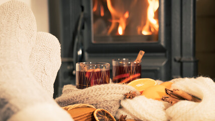 mulled wine by the fireplace, 2 glasses of drink, spices, a warm scarf and feet in warm socks near the stove