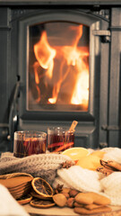 mulled wine by the fireplace, 2 glasses of drink, spices and a warm scarf by the stove