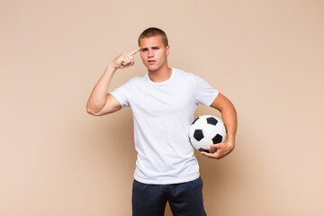young blonde man feeling confused and puzzled, showing you are insane, crazy or out of your mind