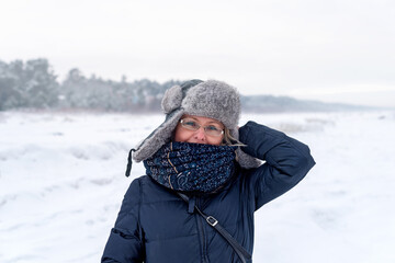 Fototapeta na wymiar Smiling woman on the background of winter landscape, Jurmala, Latvia. Winter walk.