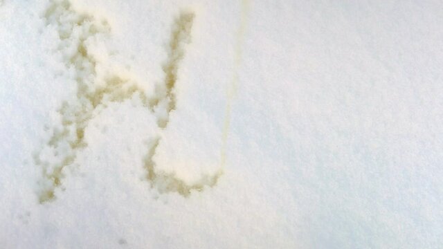 The inscription hello is written in the snow with a yellow stream of water