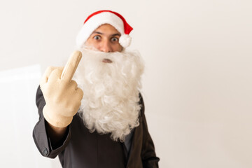 Middle age handsome man wearing Santa Claus costume and beard standing Showing middle finger doing fuck you bad expression, provocation and rude attitude. Screaming excited