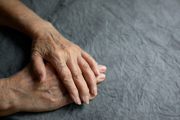 Hands of an elderly seigneur on a gray faded tablecloth. Senior old lady experiencing severe...