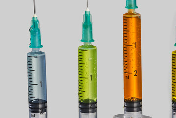 close-up of four syringes with colored vaccine