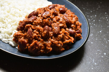 Chilli con carne with rice on a blue plate.  Traditional Mexican food. 