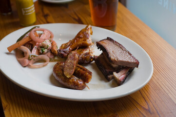 Barbecue catering platter with variety of meats. Traditional Texas BBQ: Beef brisket, beef ribs, pork ribs, sausage links, black pepper roasted chicken, and turkey served with homemade sauce.