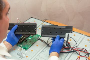 Repair of LCD TV in service center. The engineer is holding left and right monitor speakers....