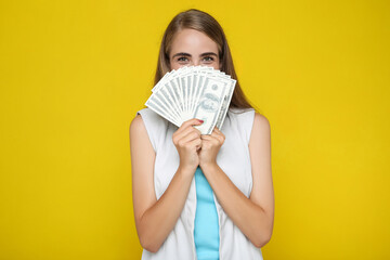 Beautiful woman holding dollar banknotes on yellow background