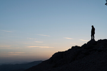 Silhouettes of man  on top of a mountain.