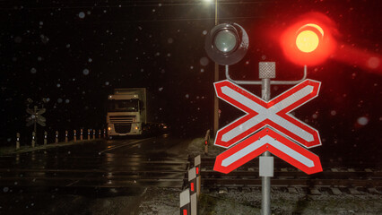 Railroad crossing with passing train by night. Train crossing gates closed on rural road at late...