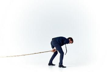 business man with a rope in his hands on a light background tension model of achieving the goal