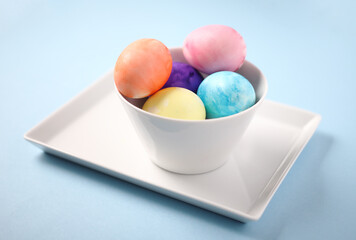 colored eggs in a white bowl on a blue background