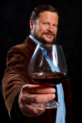 Stylish bearded man dressed in brown jacket with glass of whisky