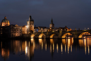 Fototapeta na wymiar illuminated stone Charles Bridge and the flowing river Vltava and lights from street lighting in the center of Prague in the Czech Republic at night