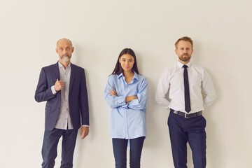 Office employees of different ages and ethnicities leaning against wall and looking at camera
