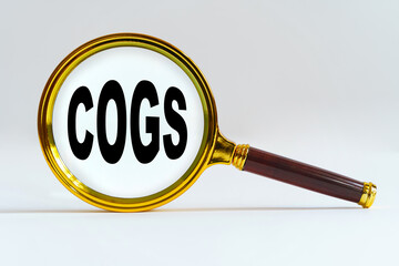 Magnifier on a white background, inside the text is written - COGS