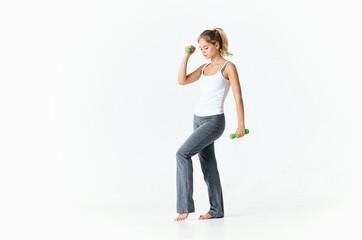 a woman in a bright room goes in for sports with dumbbells in her hands 