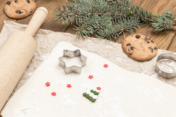 Dough for baking cookies on paper. Cookie cutter molds. Ready-made cookies and fir branches....